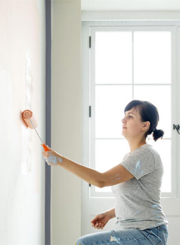 woman painting walls with paint roller