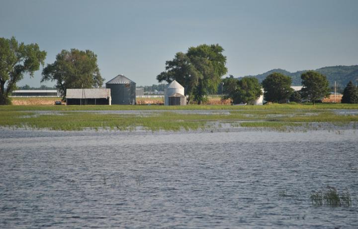 A Nebraska farm with flooded acres of cropland in the foreground and a house and barn in the background.