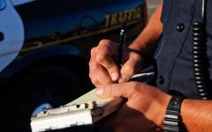 This is a close shot of a law enforcement officer's hands and he writes a citation. 
