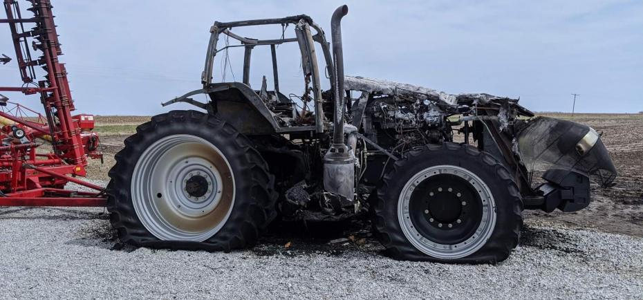 The Nedrows' blackened tractor sits against a bright blue sky following a tractor fire in April of 2020. The planter behind it is largely unscathed.