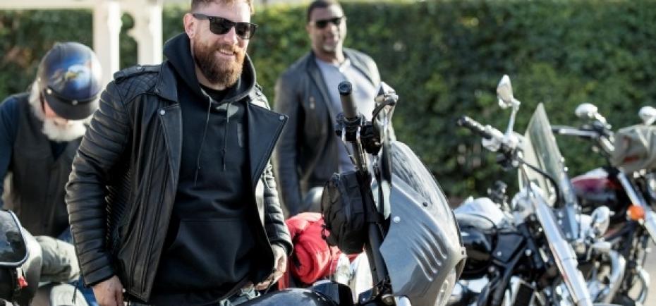 Three motorcyclists prepare to get on their bikes on a spring day.