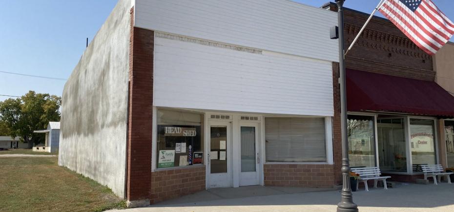 A 1915 one-story retail building is pictured in Fairmont, NE. Its vintage front exterior pairs brick with crisp, white finishes. The building sits on the recently renovated Main Street. 