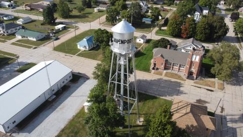 This drone pic looks downward on the Davenport water tower and surrounding blocks. It's shot in summer, with green grass and full canopies on the trees lining the streets.