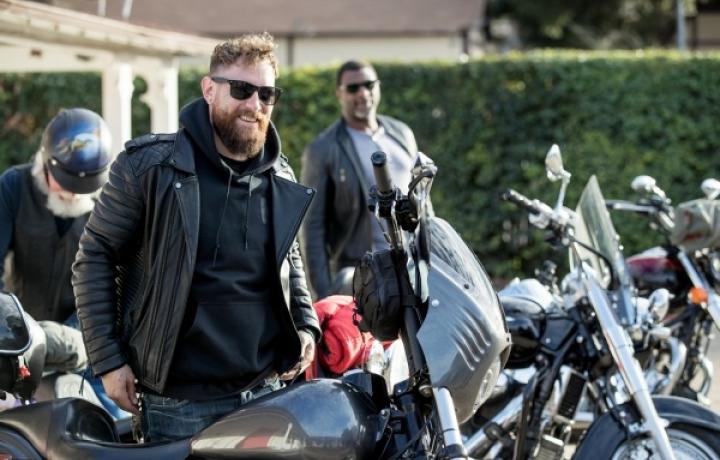 Three motorcyclists prepare to get on their bikes on a spring day.