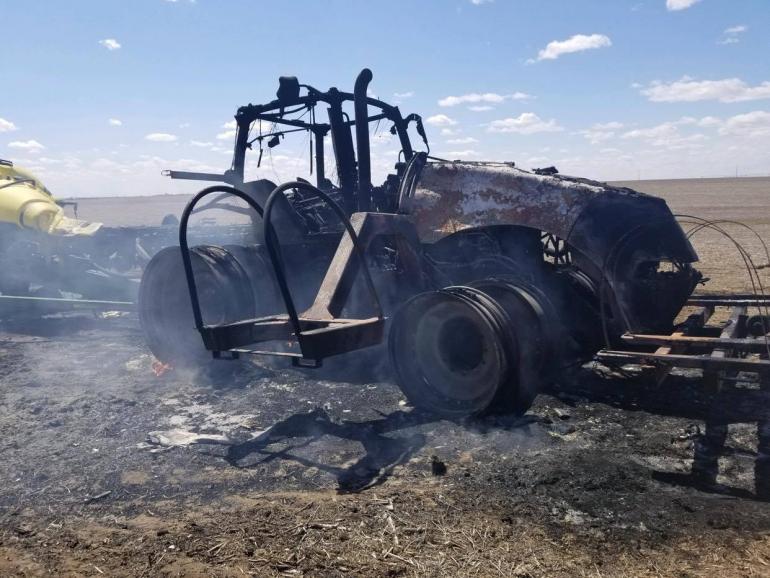 Only the charred outline of a 2012 Case IH tractor remains in this photo taken after the fire. The tractor sits in a wide open, unplanted field.