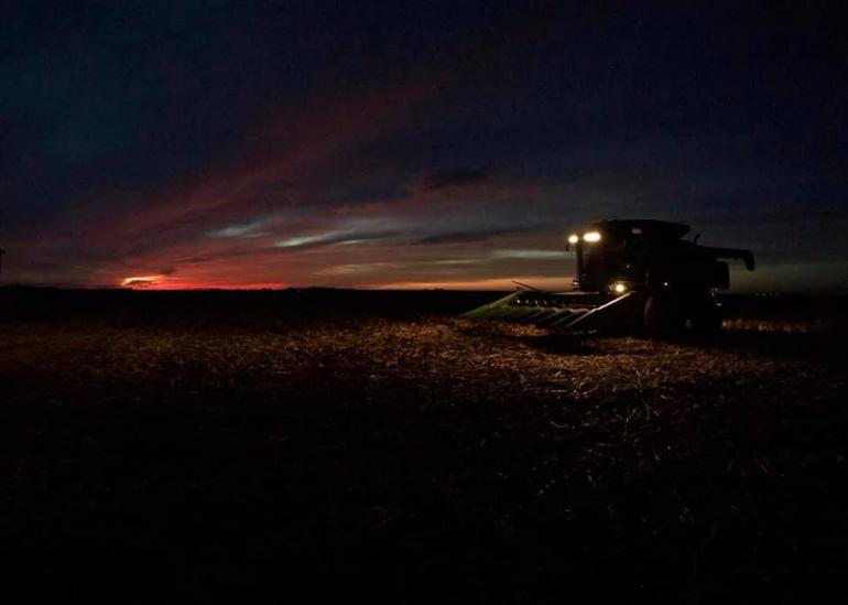 The camera captures the last rays of a fall harvest day. The sky is almost black, with the last reds and oranges sinking into the horizon.