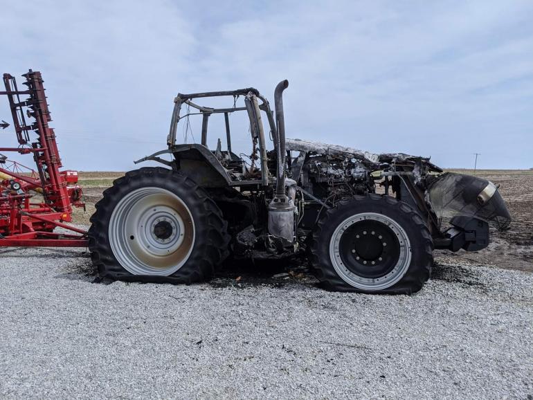 The Nedrows' blackened tractor sits against a bright blue sky following a tractor fire in April of 2020. The planter behind it is largely unscathed.