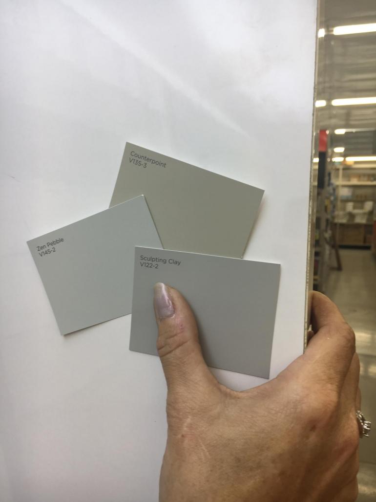 Three beige and gray paint strips are held up to a white background. They are the most popular neutral colors sold at Geneva Home Center.