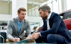 Car salesman and customer signing documents