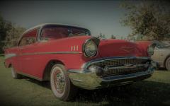 A shiny red 1957 Chevrolet Bel Air is on display at a campground car show.