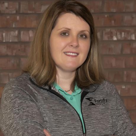 Jennifer Asche, business manager at Fortify Group's Geneva office, is pictured in front of a brick wall at the office.